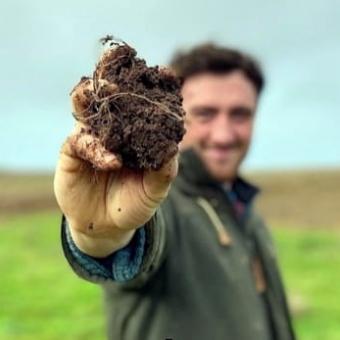 Man holding up a clump of soil close to the camera